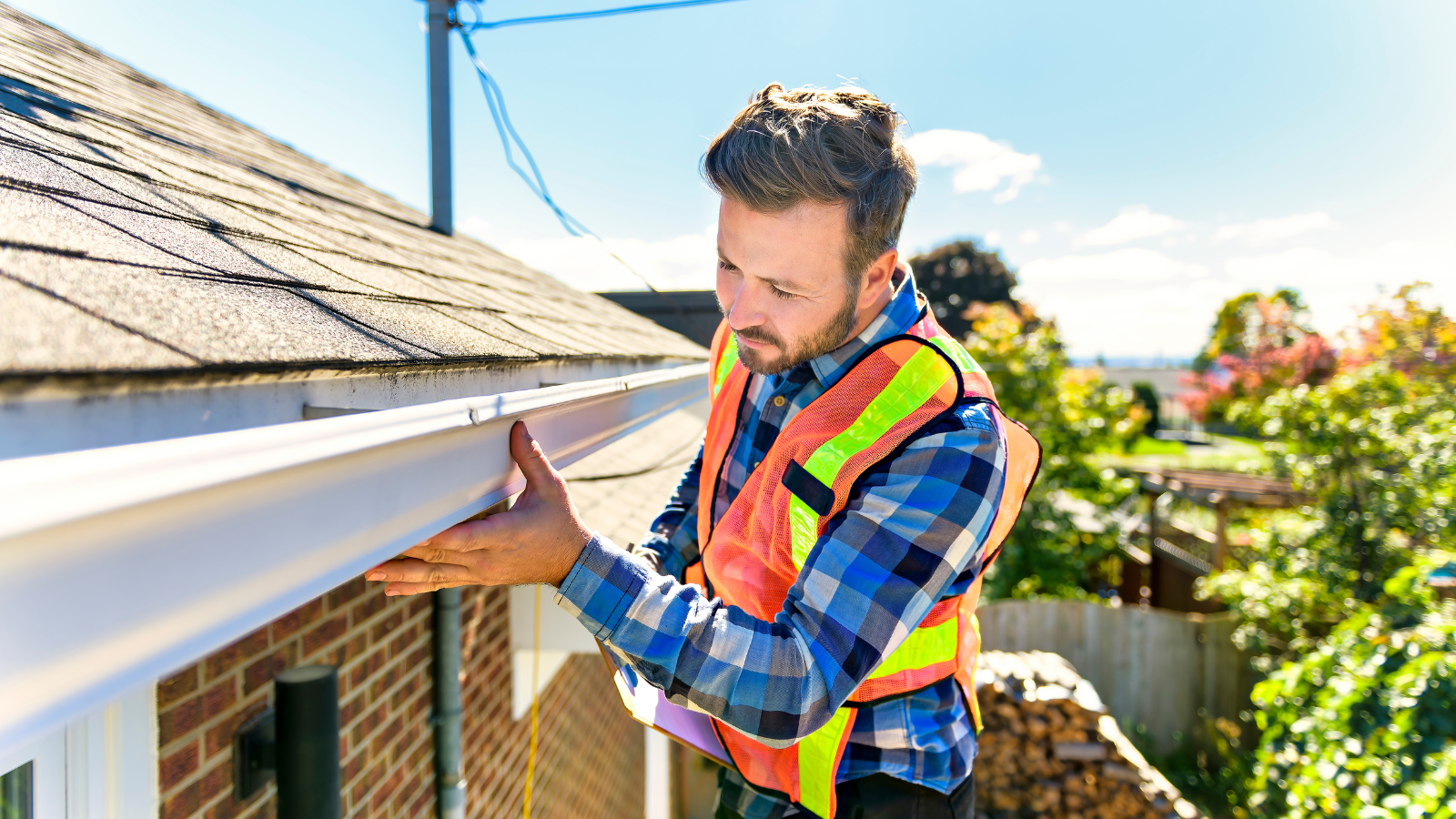 A professional roofer checking the gutter for damage.